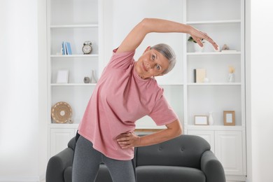 Photo of Senior woman in sportswear stretching at home