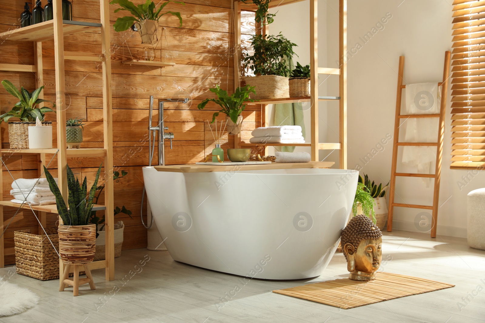 Photo of Stylish bathroom interior with white tub and green houseplants near wooden wall. Idea for design