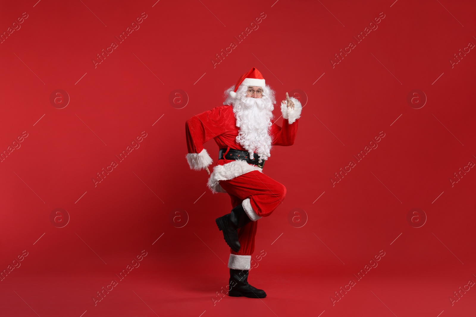 Photo of Merry Christmas. Santa Claus dancing on red background