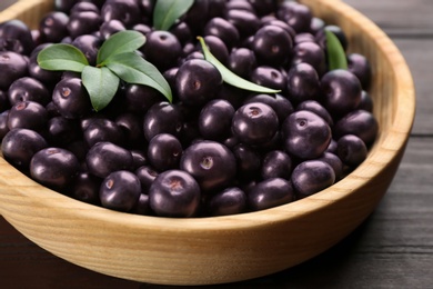 Photo of Tasty acai berries in wooden bowl on table, closeup