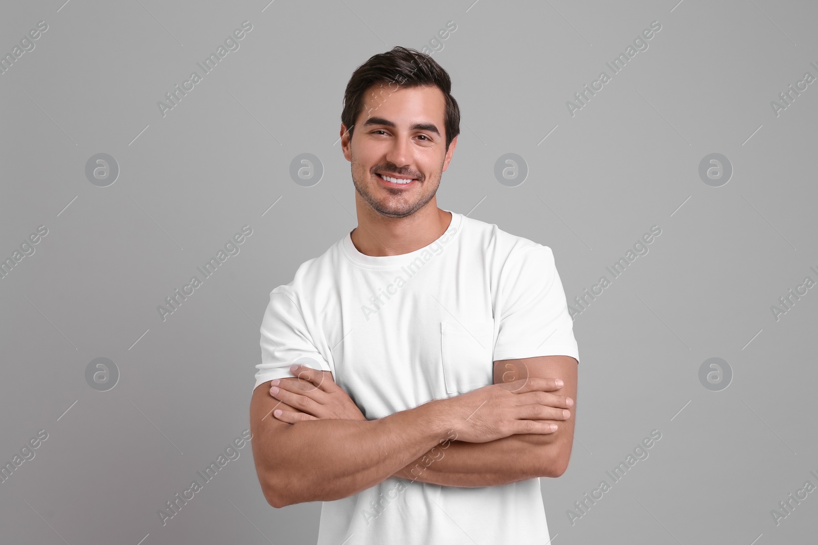 Photo of Portrait of handsome young man in white t-shirt on grey background
