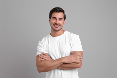 Portrait of handsome young man in white t-shirt on grey background