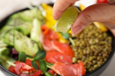 Photo of Woman adding lemon juice to salad with mung beans, closeup. Space for text