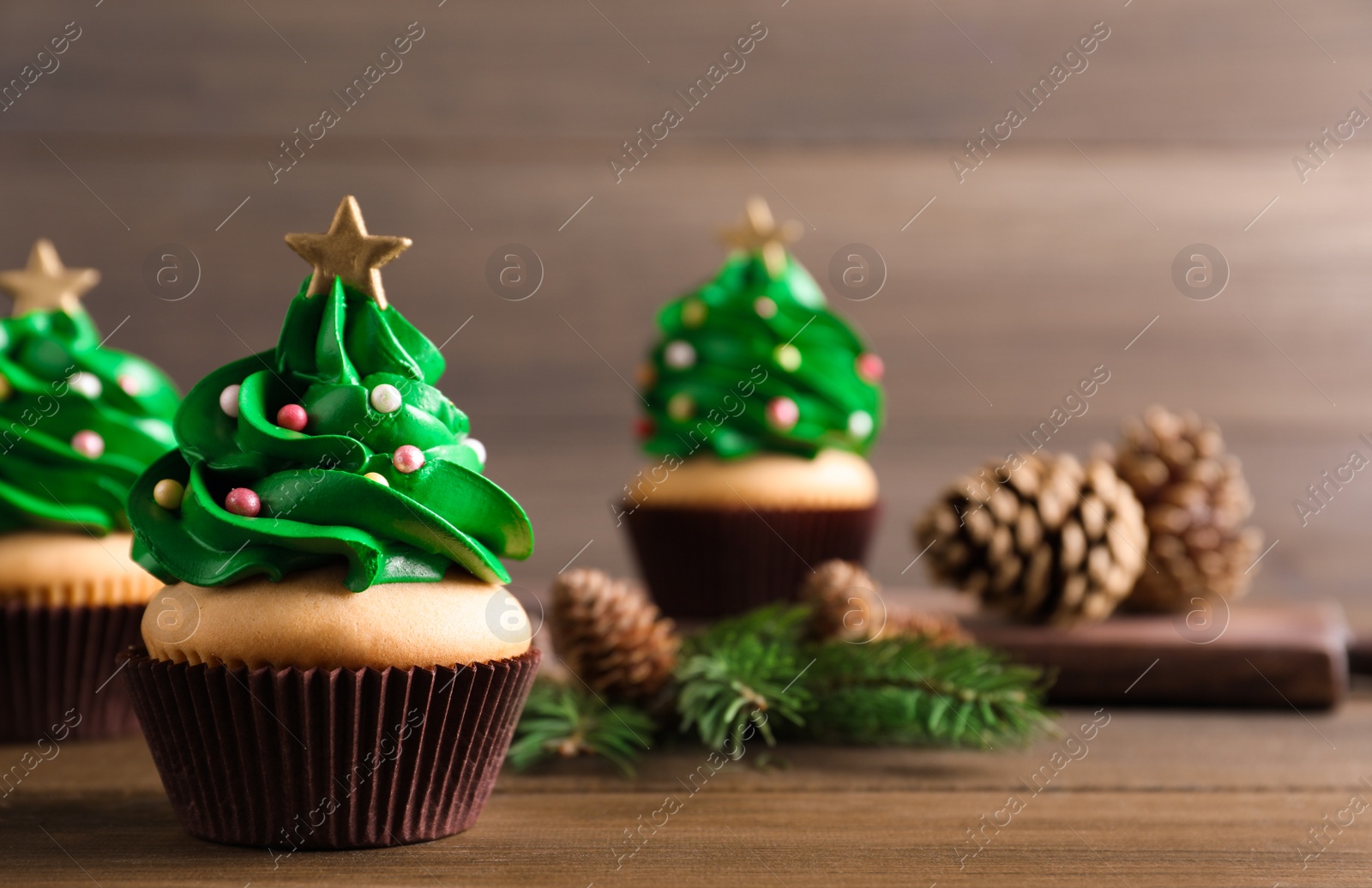 Photo of Christmas tree shaped cupcakes on wooden table. Space for text