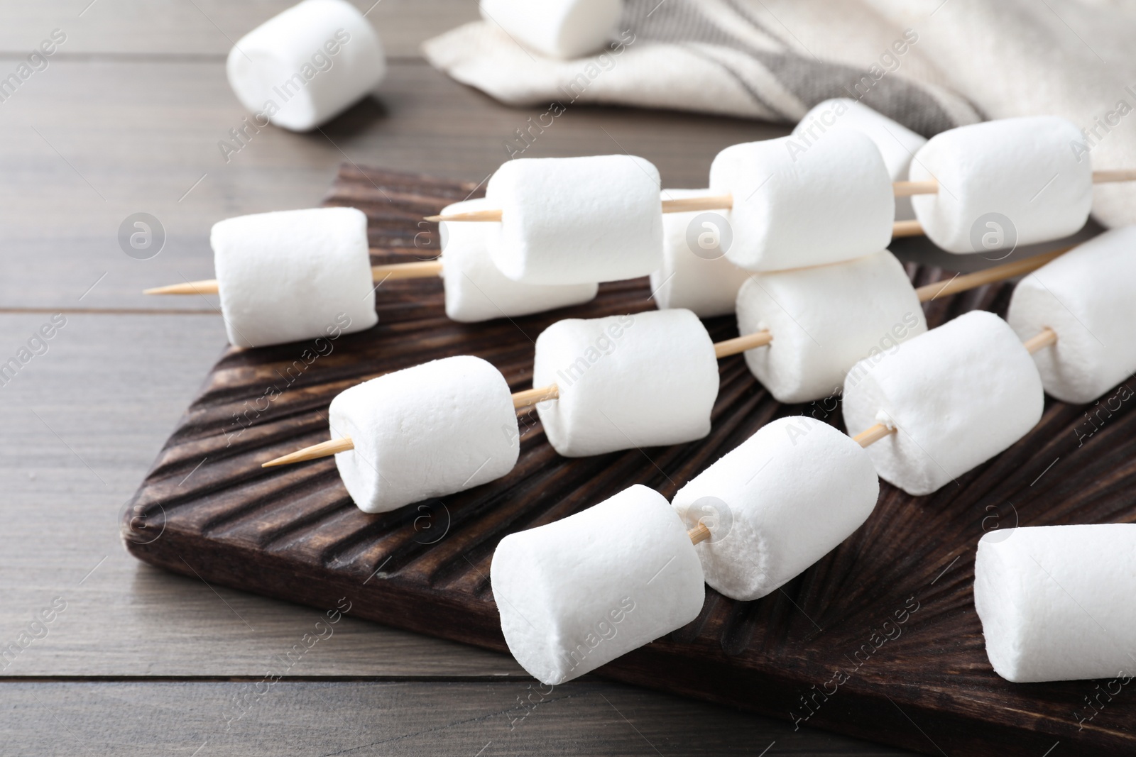Photo of Sticks with marshmallows on wooden table, closeup
