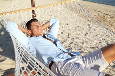 Photo of Handsome man relaxing in hammock on beach