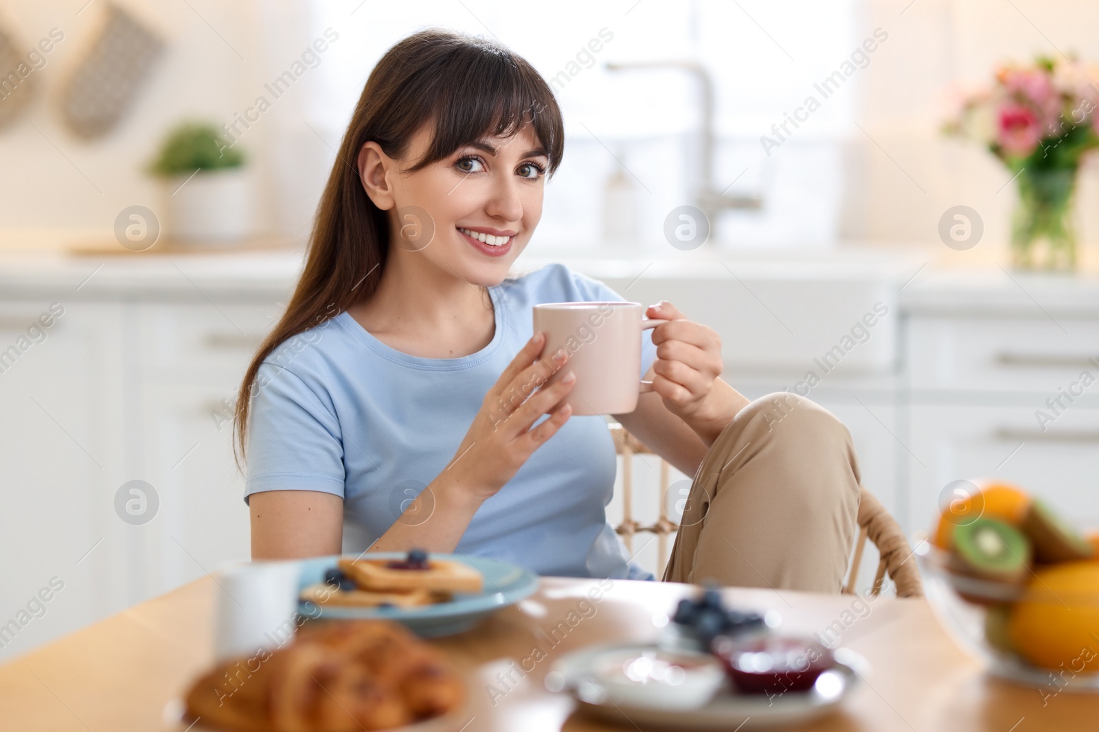 Photo of Smiling woman drinking coffee at breakfast indoors