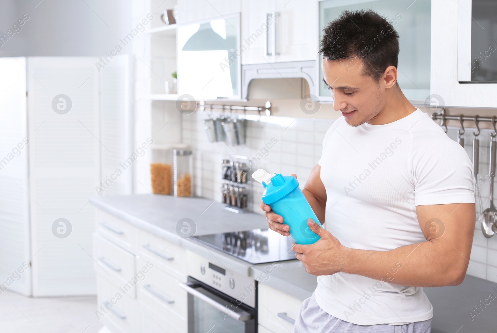 Photo of Man with bottle of protein shake in kitchen. Space for text