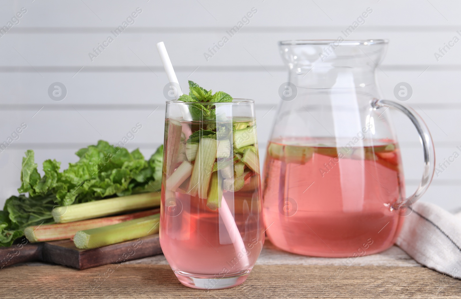 Photo of Tasty rhubarb cocktail and stems on wooden table