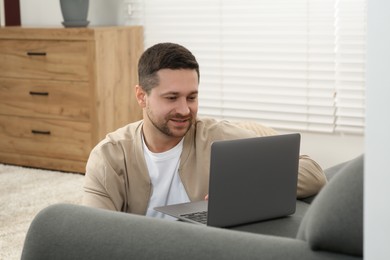 Photo of Man working with laptop on couch at home