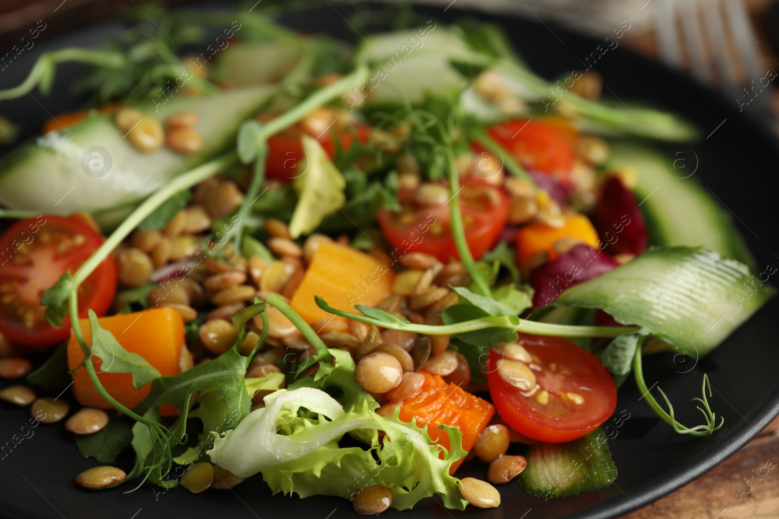 Photo of Delicious salad with lentils and vegetables on plate, closeup