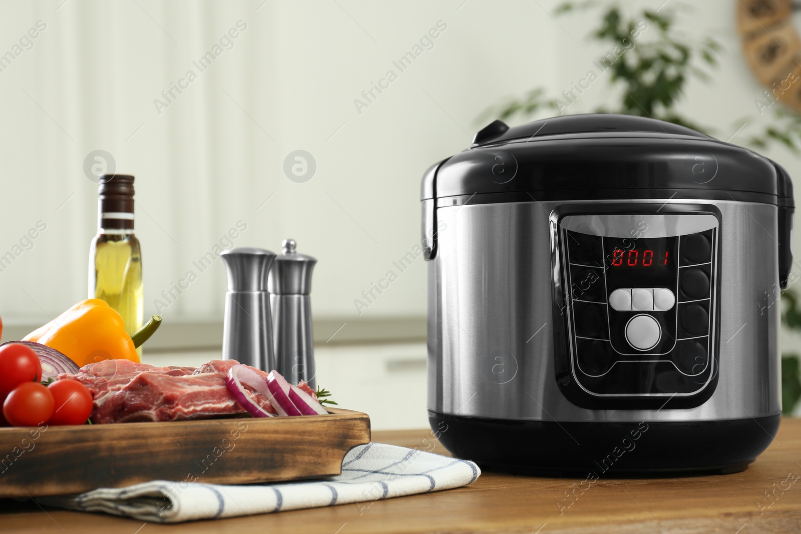 Photo of Modern multi cooker and products on wooden table in kitchen. Space for text