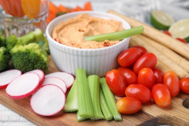 Board with delicious hummus, grissini sticks and fresh vegetables, closeup