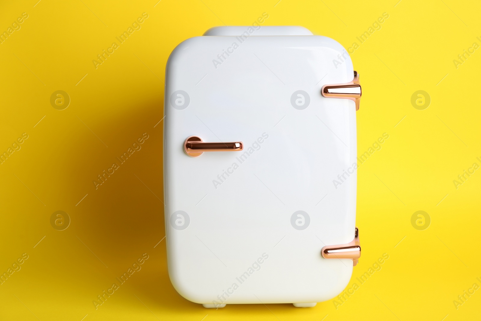 Photo of Mini refrigerator for cosmetics on yellow background