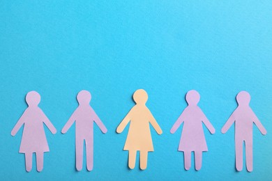 Photo of Many different paper human figures on light blue background, flat lay with space for text. Diversity and inclusion concept