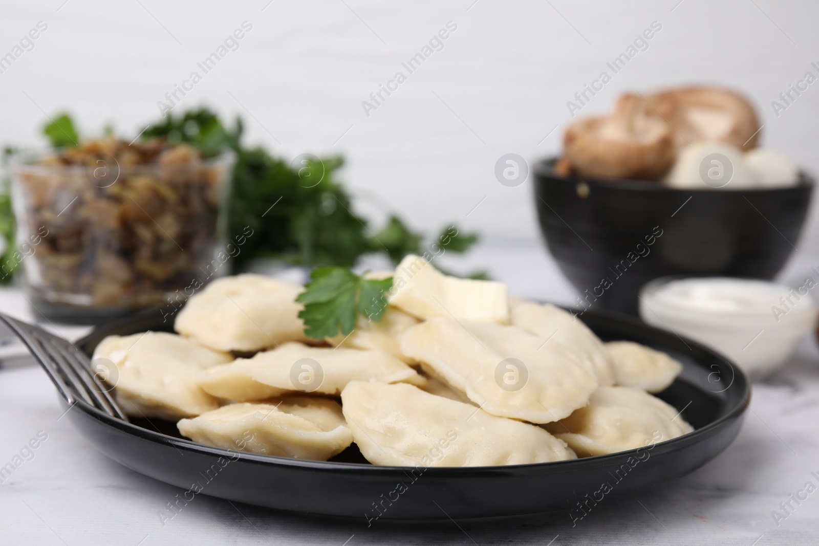 Photo of Delicious dumplings (varenyky) with tasty filling, butter and parsley served on white table, closeup
