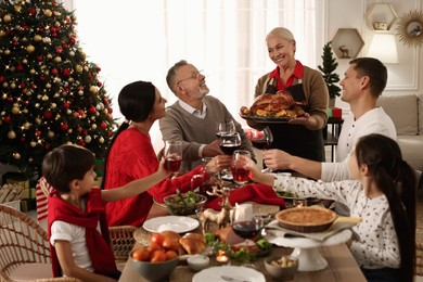 Photo of Happy family clinking glasses of drinks at festive dinner indoors. Christmas celebration