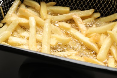 Photo of Cooking delicious french fries in hot oil, closeup