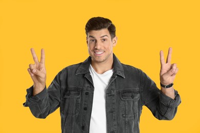 Man showing number four with his hands on yellow background