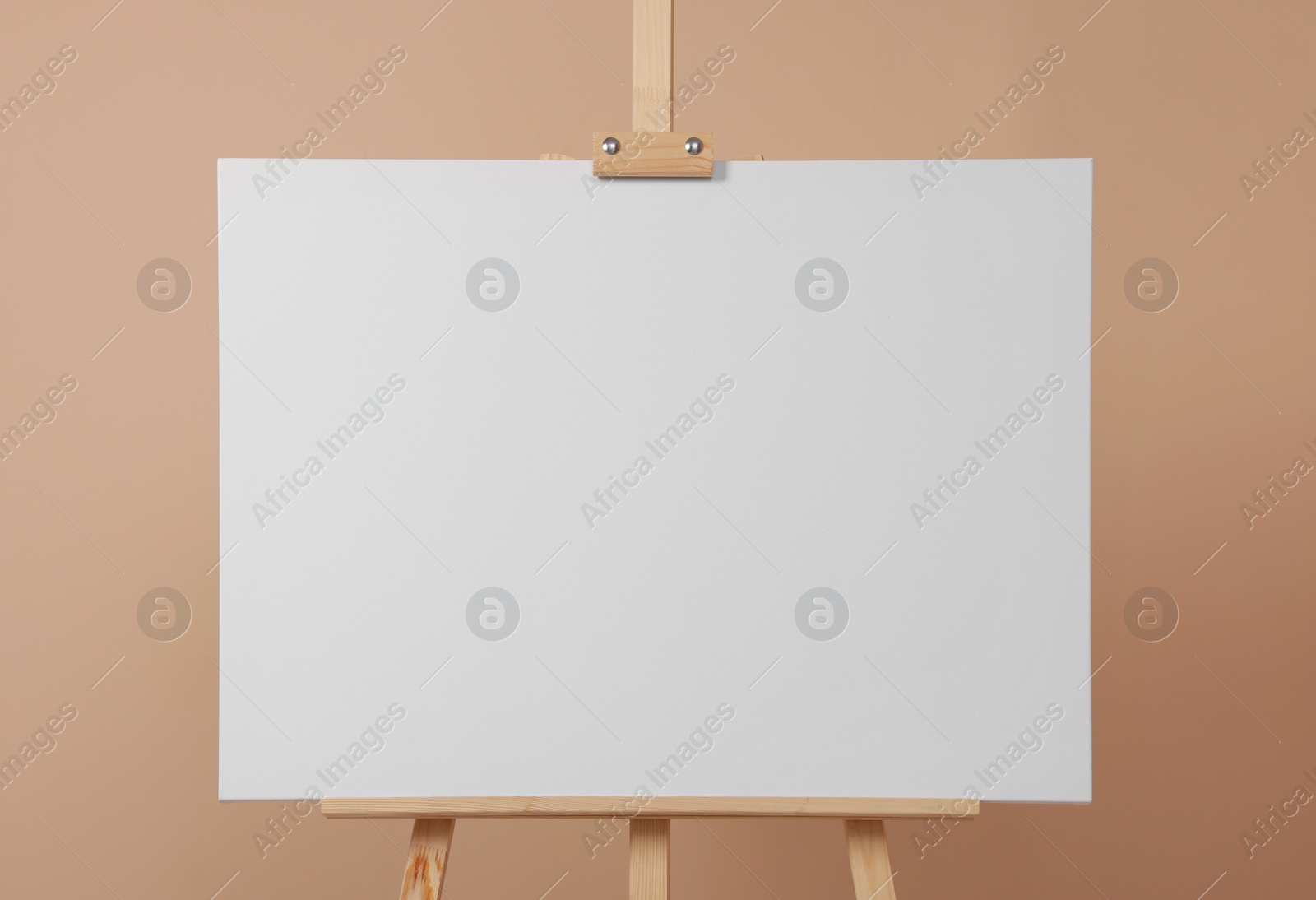 Photo of Wooden easel with blank canvas on beige background