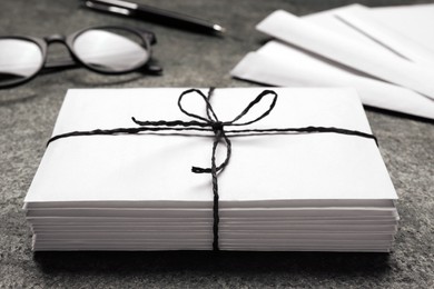 Photo of Stack of letters tied with string on grey table, closeup