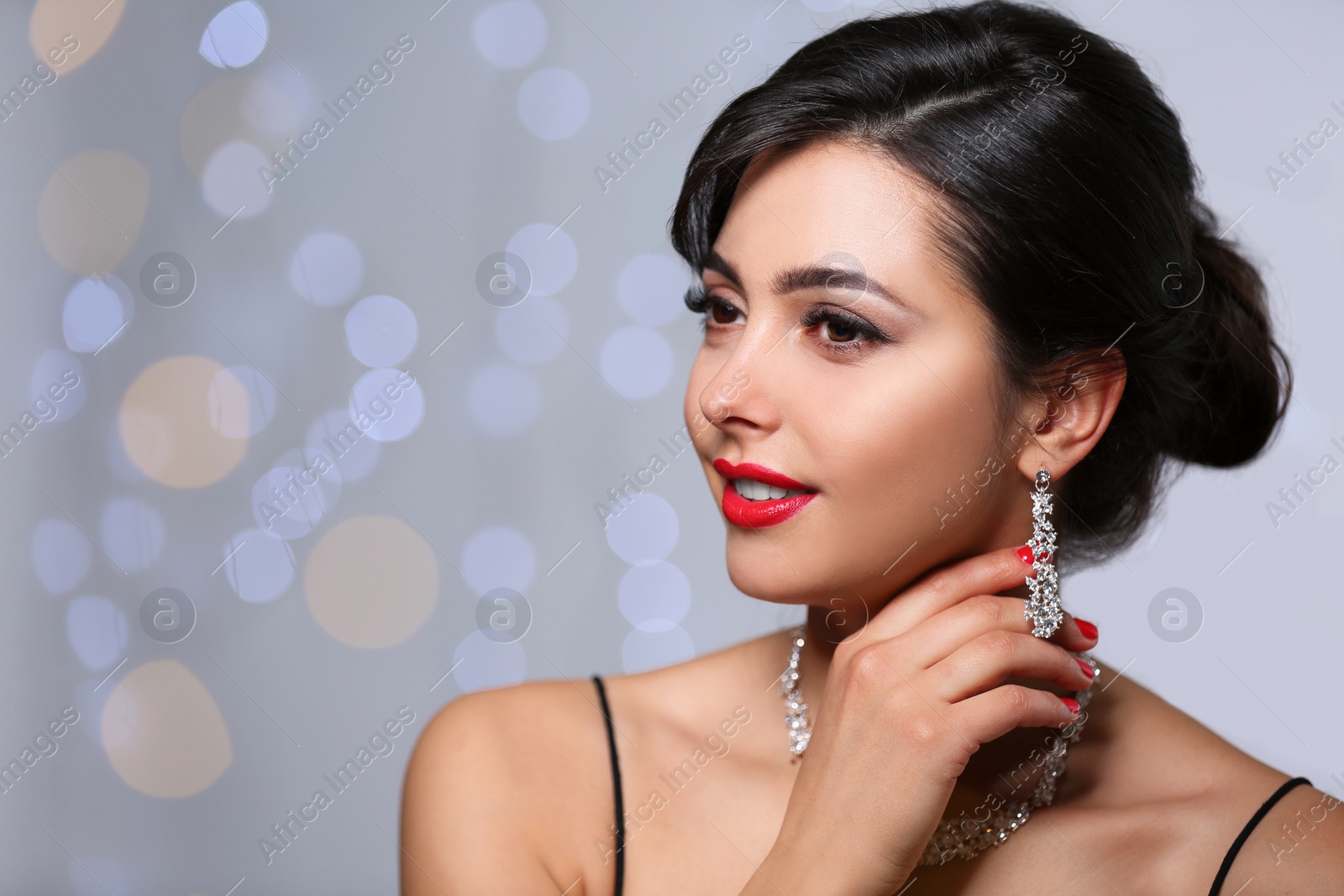 Photo of Beautiful woman with elegant jewelry on blurred background. Space for text