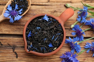 Flat lay composition with dry tea leaves and cornflowers on wooden table