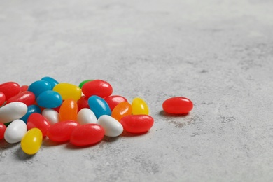 Delicious bright jelly beans on stone background, closeup. Space for text