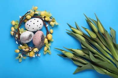 Flat lay composition with flowers and eggs on light blue background. Easter celebration