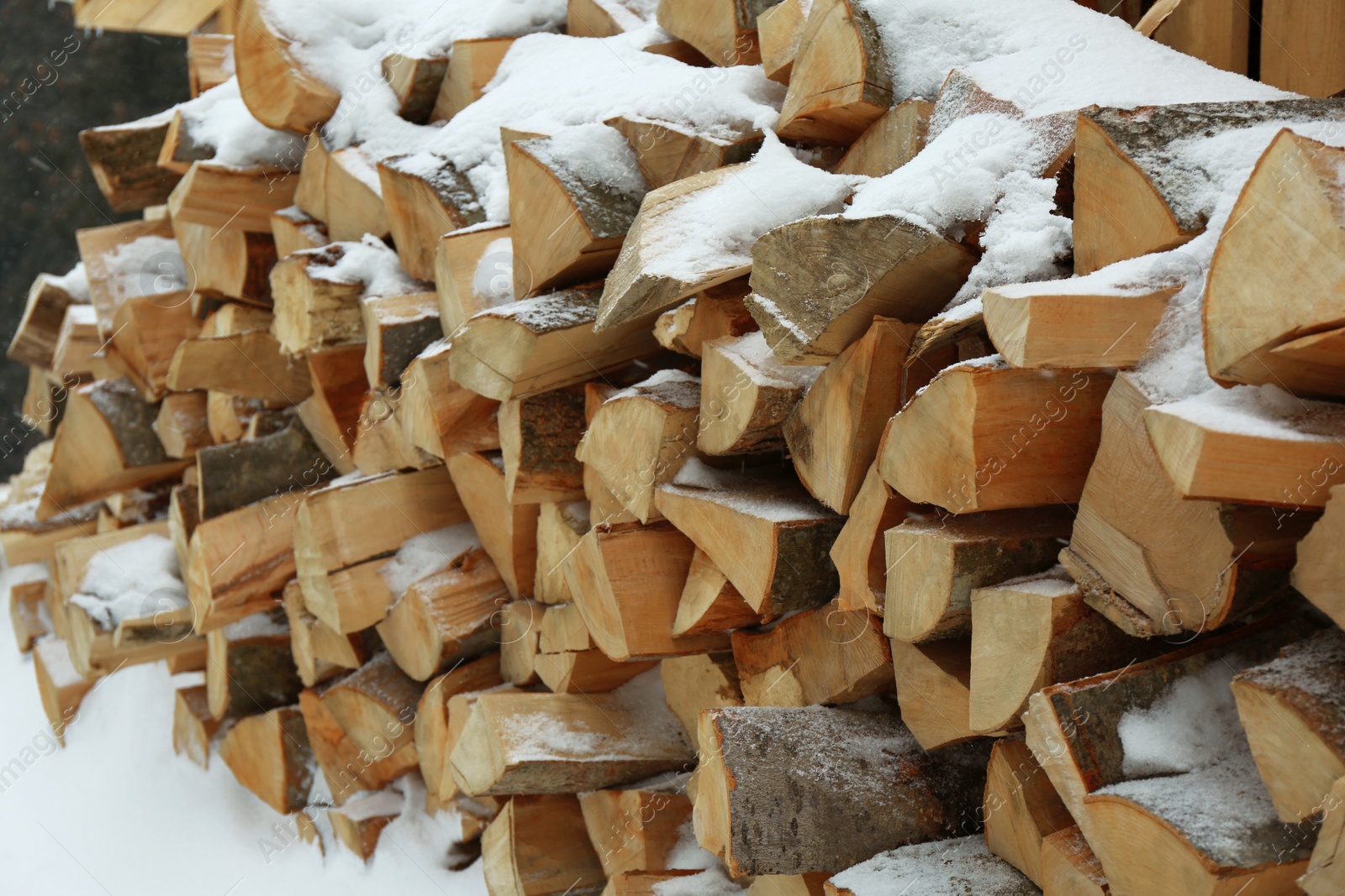 Photo of Many stacked firewood with snow in winter outdoors