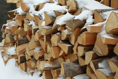 Photo of Many stacked firewood with snow in winter outdoors