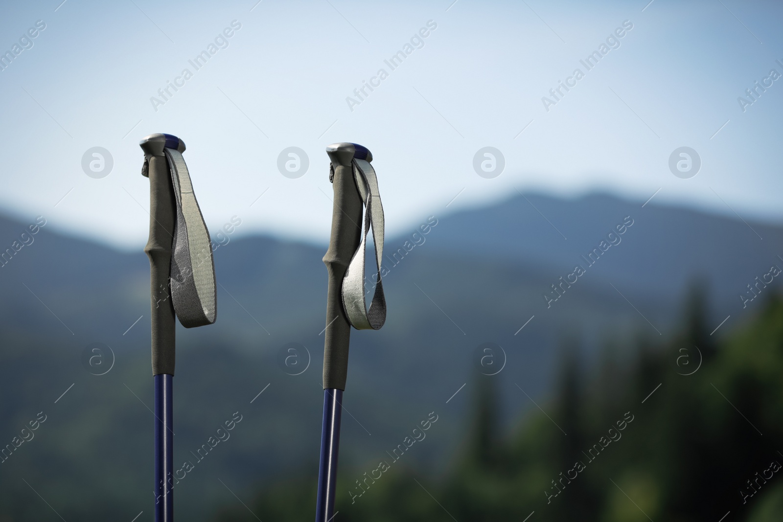 Photo of Trekking poles in mountains, space for text. Hiking accessory