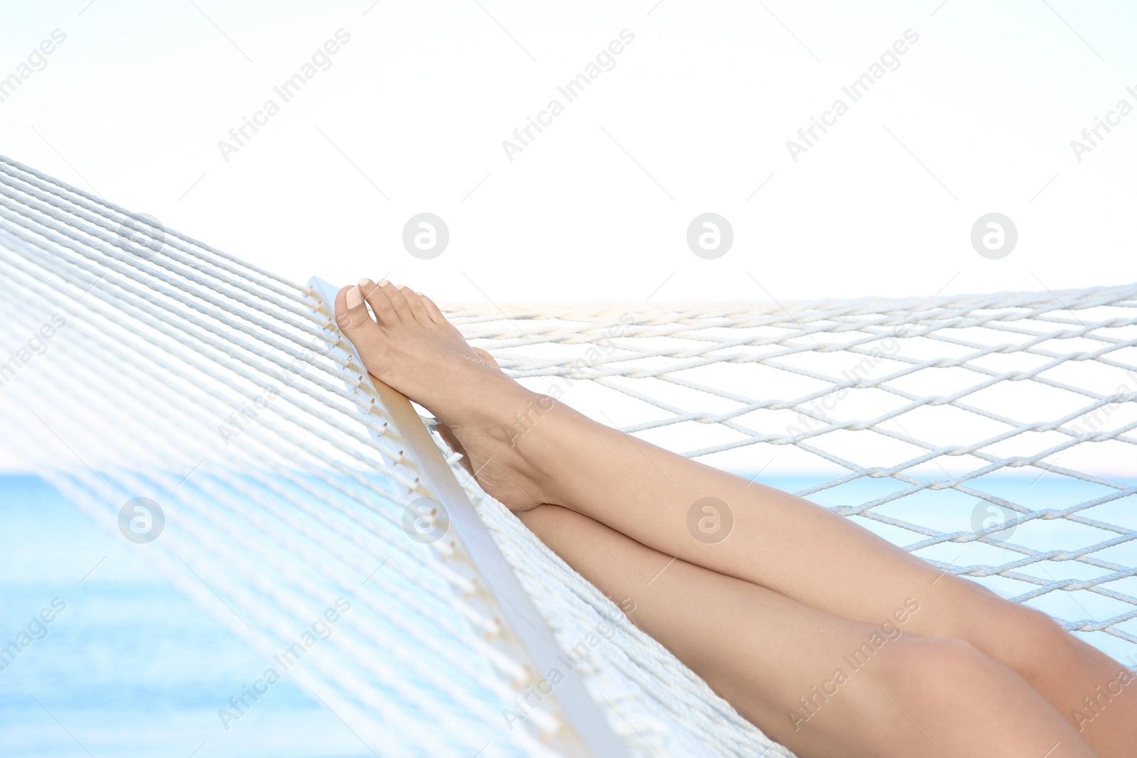 Photo of Young woman resting in hammock at seaside. Summer vacation