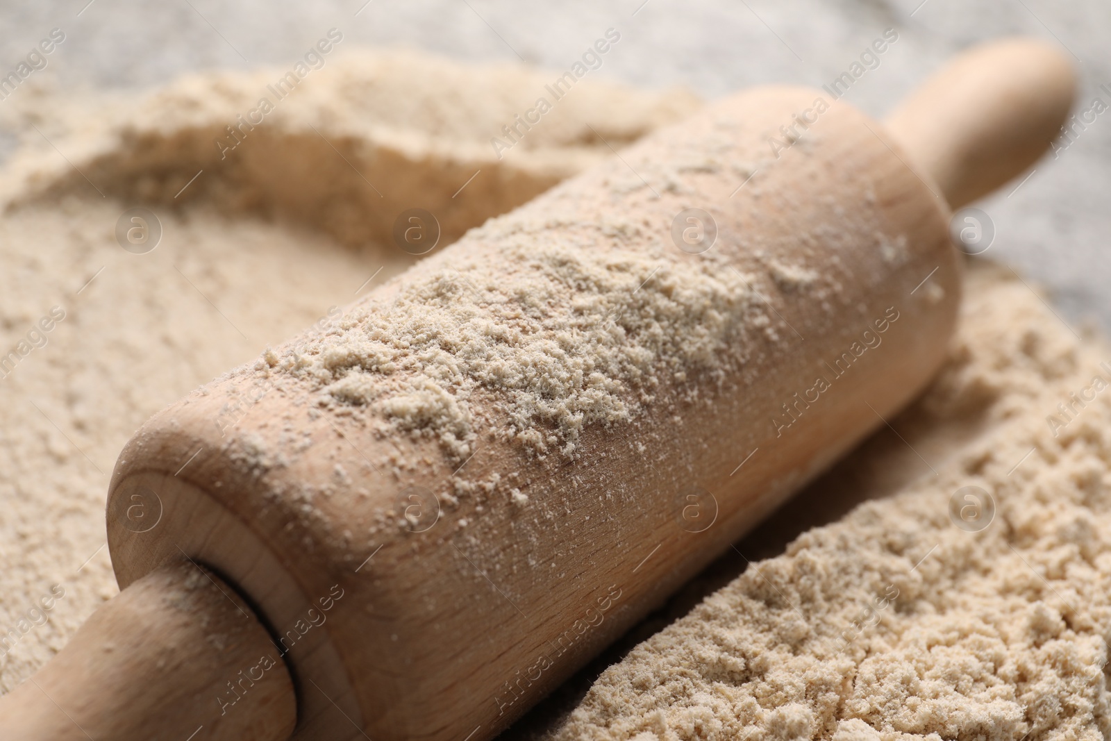 Photo of Rolling pin and flour on table, closeup