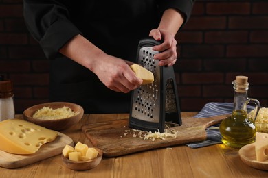 Woman grating cheese at wooden table, closeup