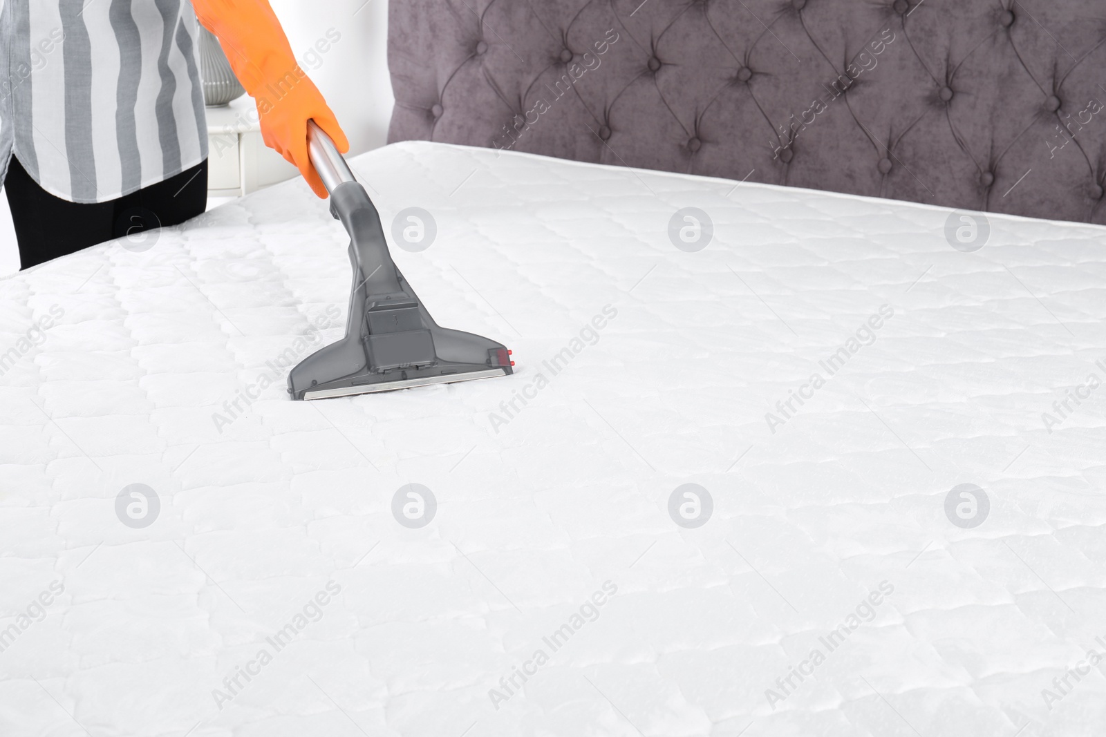 Photo of Woman disinfecting mattress with vacuum cleaner, closeup. Space for text