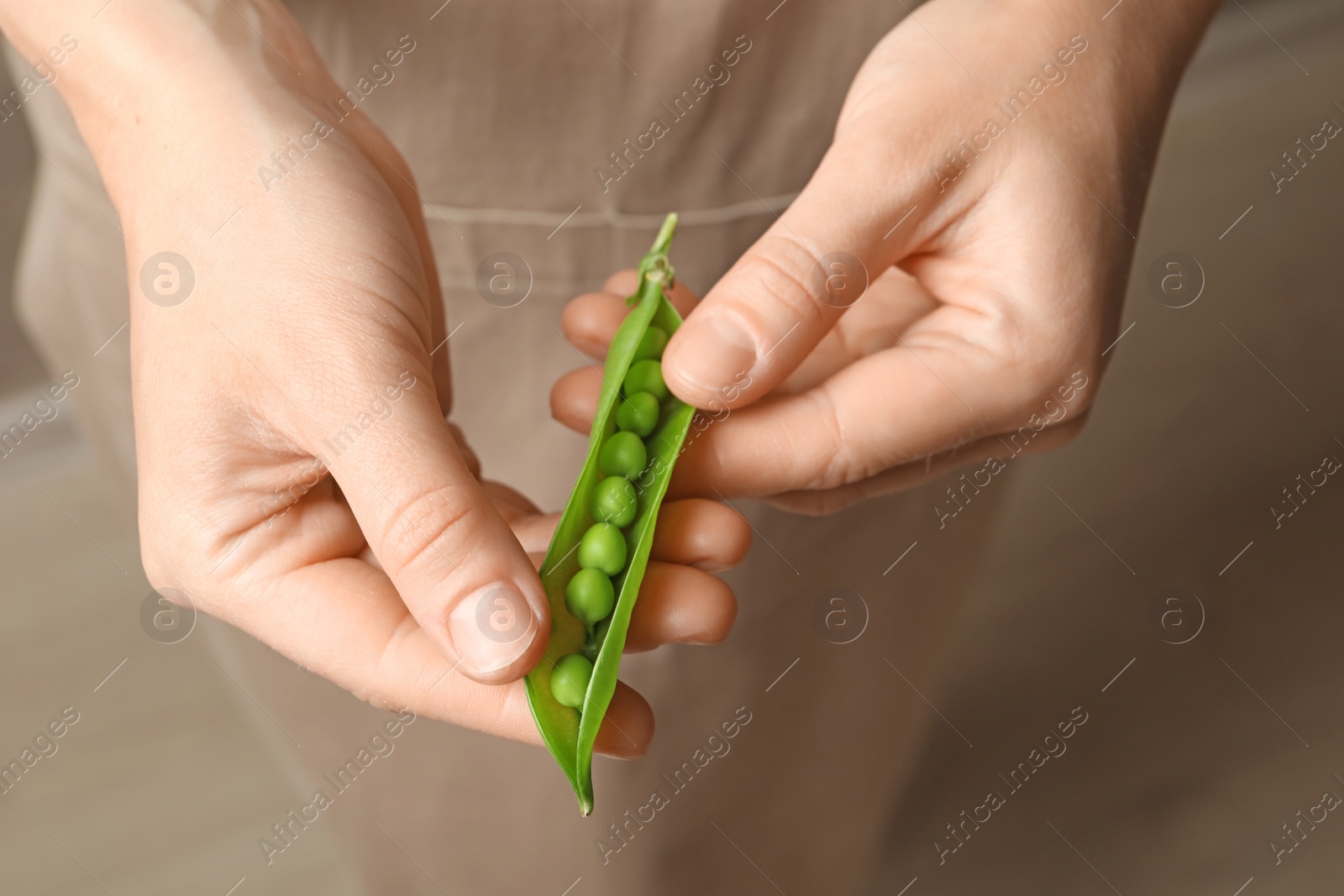 Photo of Young woman shelling fresh green peas, closeup