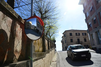 Traffic mirror near road with car on sunny day