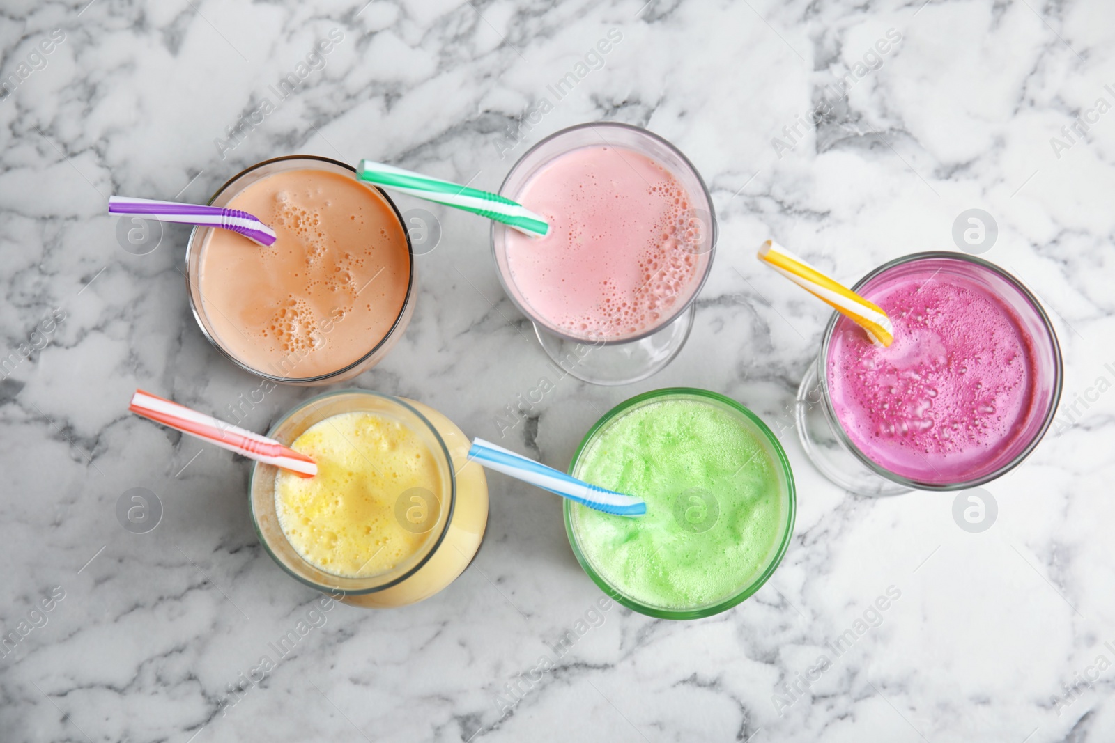 Photo of Glasses of tasty milk shakes on marble background, top view