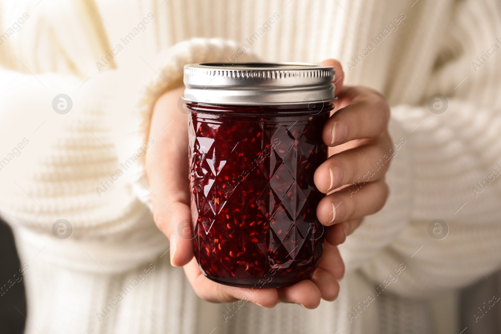 Photo of Woman with jar of raspberry jam, closeup