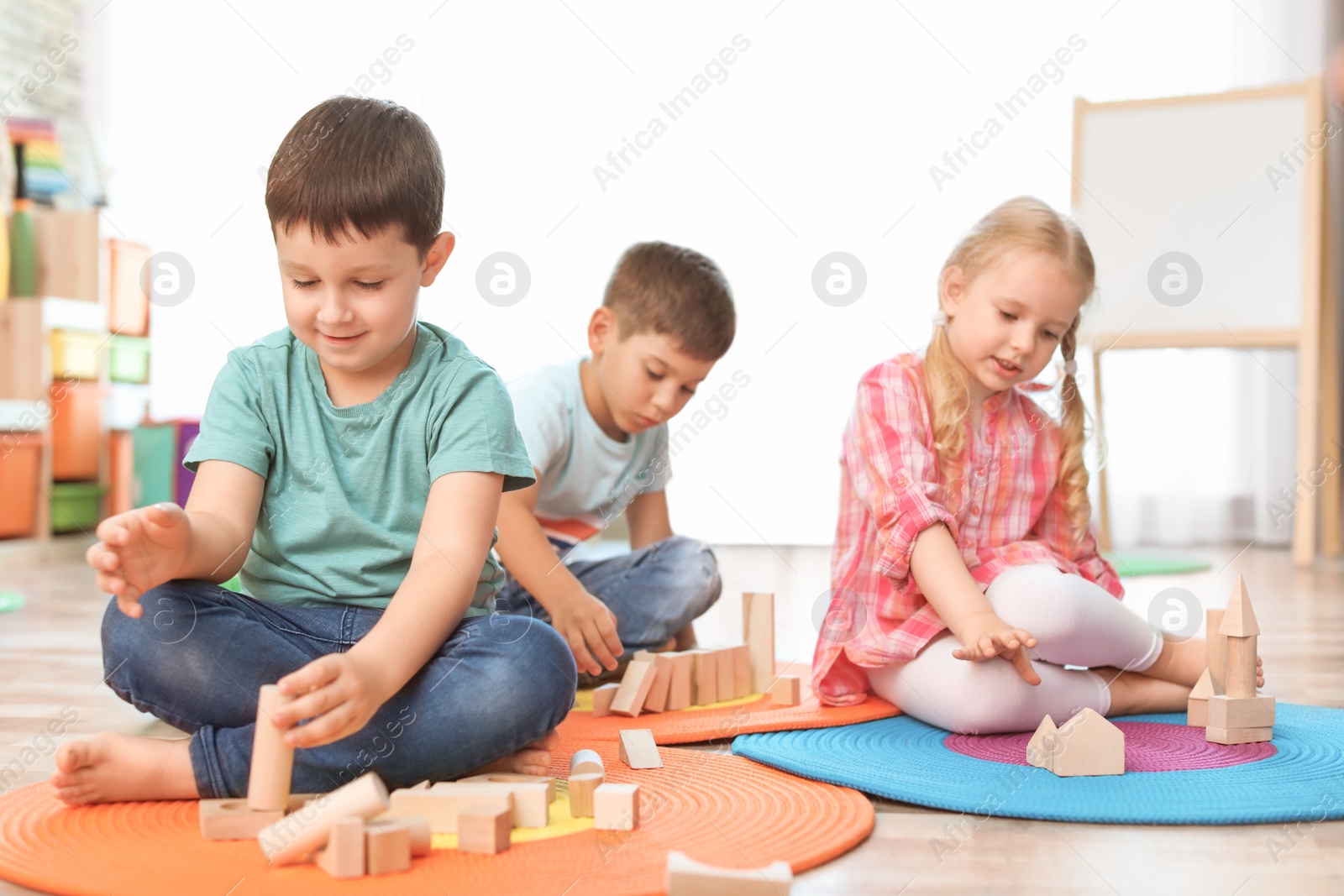 Photo of Cute little children playing with wooden blocks indoors