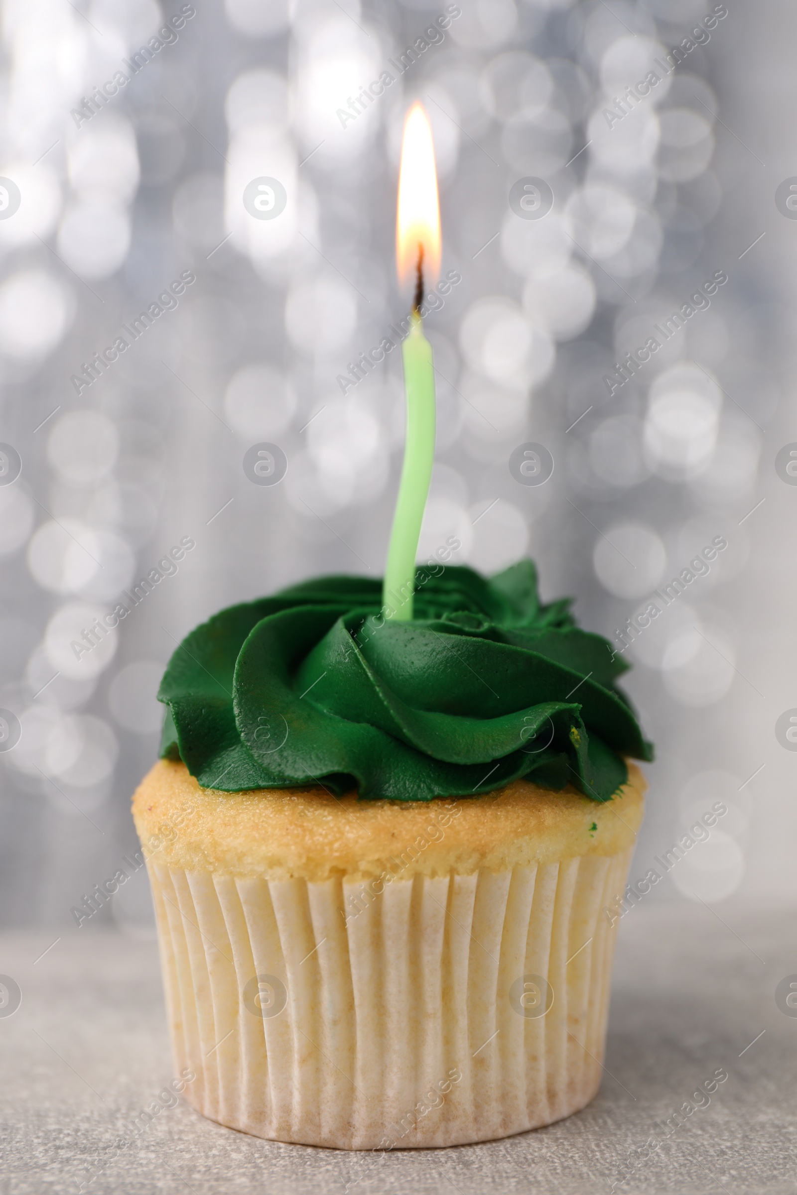 Photo of Delicious cupcake with bright cream and burning candle on grey table, closeup