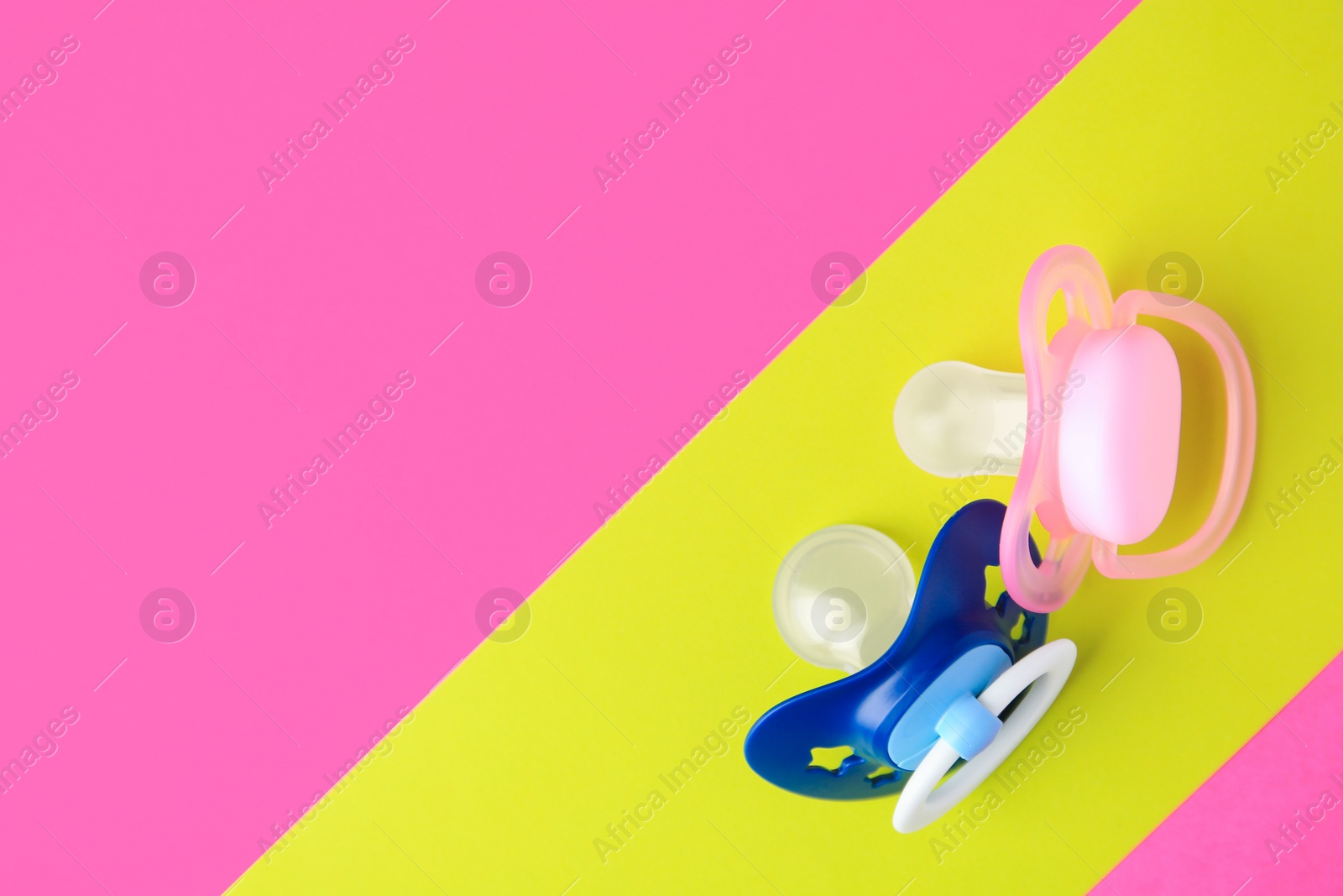 Photo of Baby pacifiers on color background, flat lay. Space for text