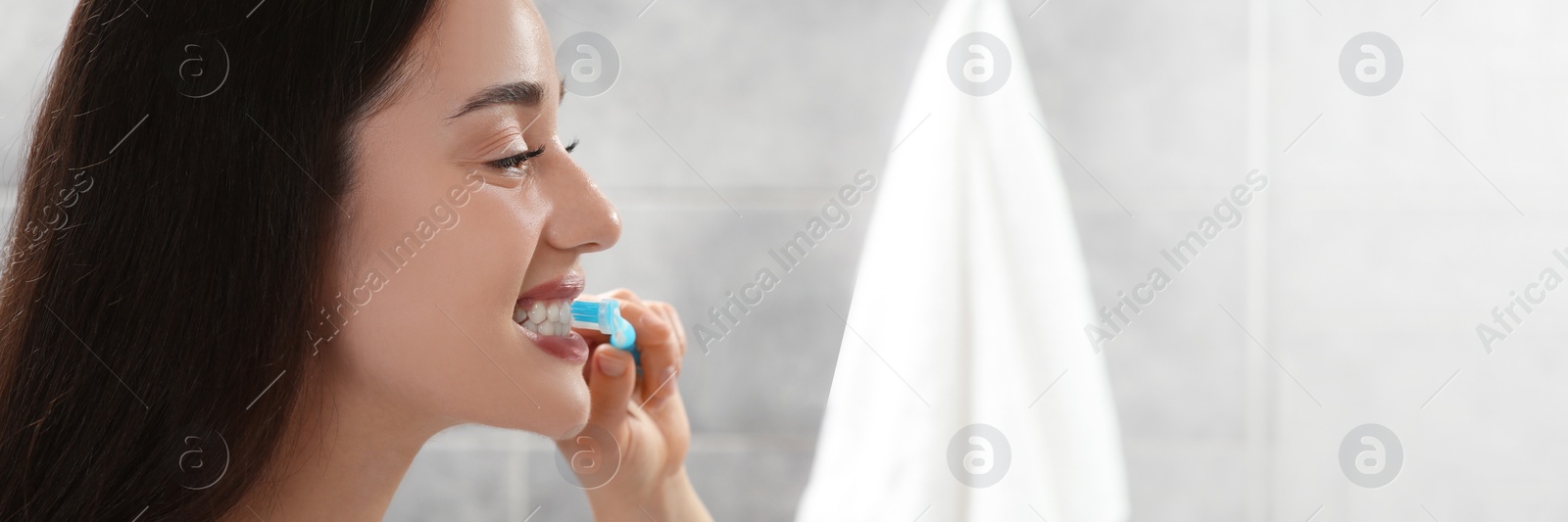 Image of Young woman brushing her teeth with plastic toothbrush in bathroom. Banner design with space for text