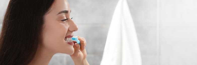 Image of Young woman brushing her teeth with plastic toothbrush in bathroom. Banner design with space for text