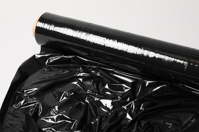 Photo of Roll of black stretch wrap on light grey background, closeup