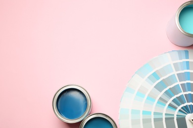 Photo of Paint cans and color palette on pink background, top view. Space for text