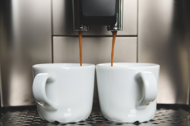 Espresso machine pouring coffee into cups, closeup