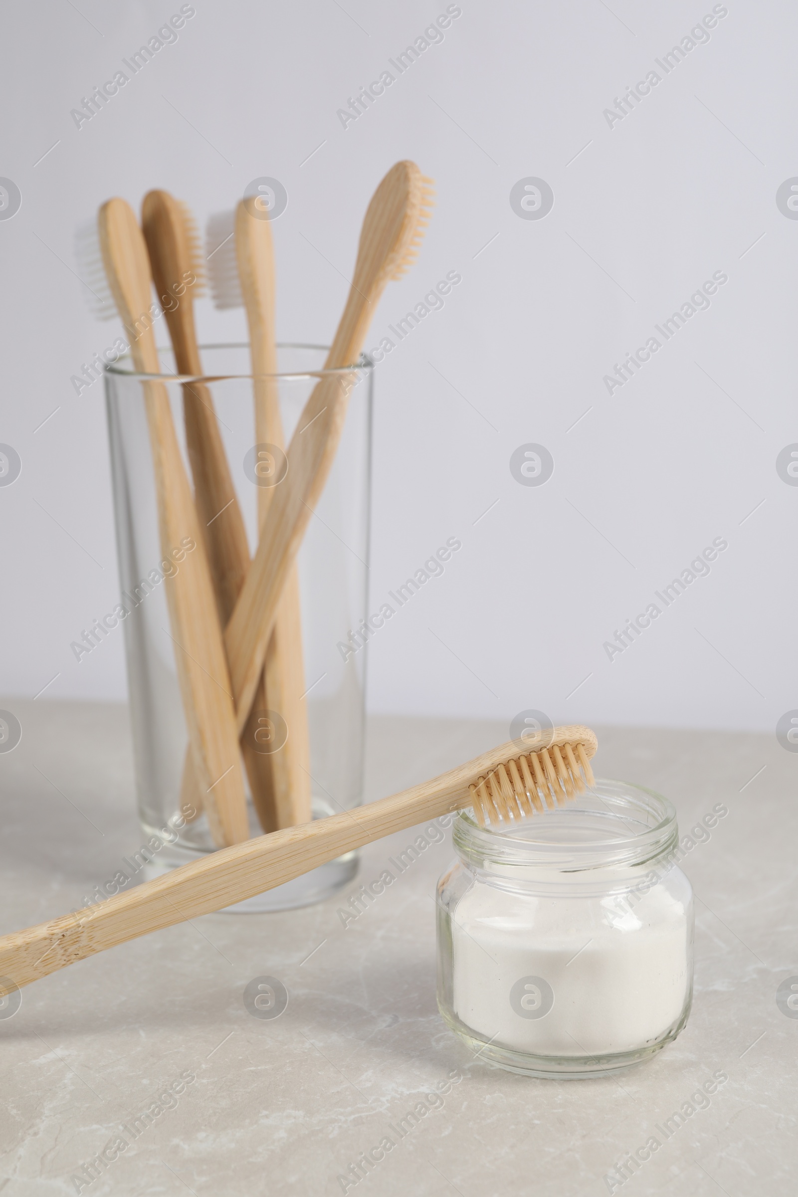 Photo of Bamboo toothbrushes and jar of baking soda on light marble table