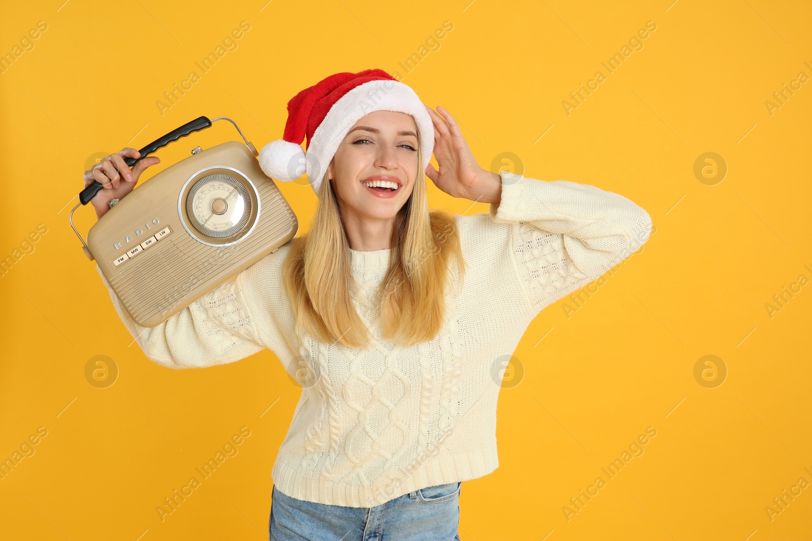 Photo of Happy woman with vintage radio on yellow background. Christmas music